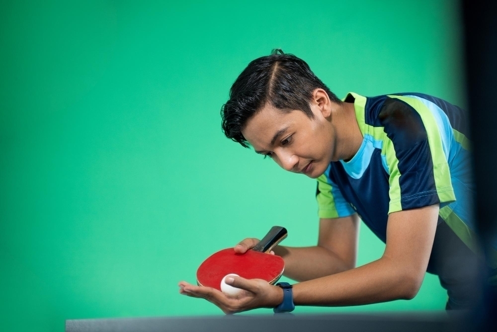 Asian athlete ready to serve during a ping pong match at green screen background