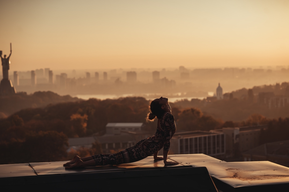 Woman doing yoga on the roof of a skyscraper in big city.