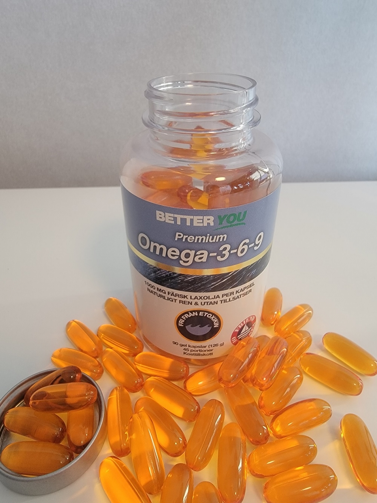 Vår egen bild av Better You Premium Omega-3, öppnad burk och gyllene kapslar