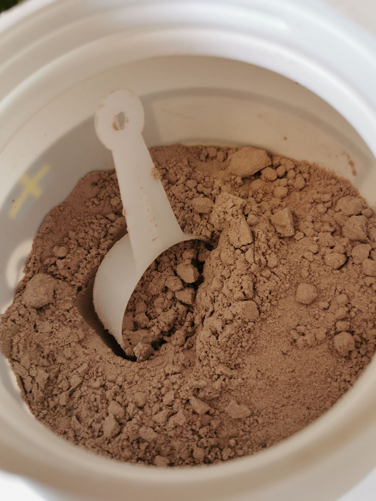 Öppnad burk med chokladpulver och skopa från Better You Gainer