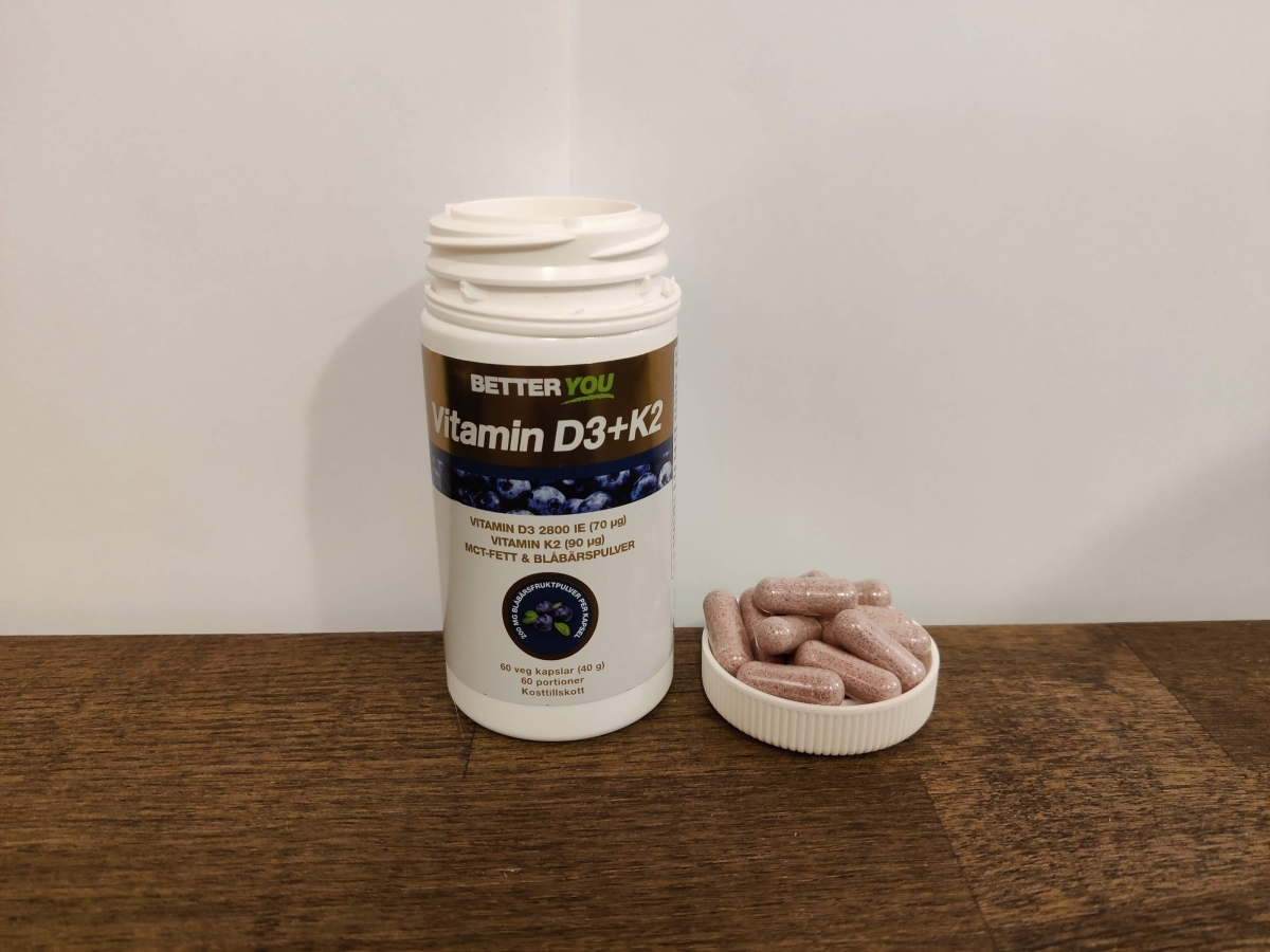 Better You Vitamin D3+K2 på träbord med kapslar bredvid locket fotograferad av oss