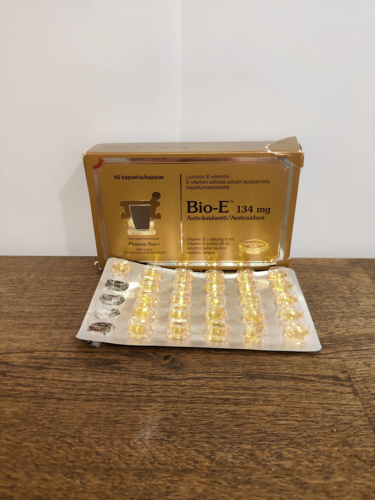 Bio-E-Vitamin på träbord med öppnat blister, flera kapslar redan använda