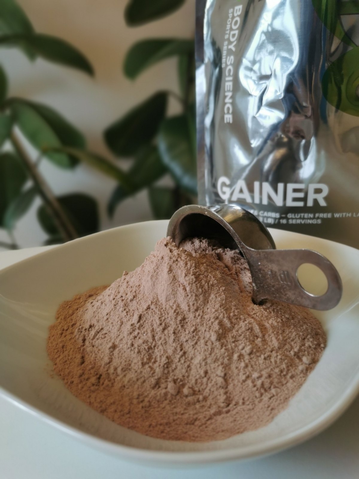 Chokladsmakad gainer som pulver i skål med metallskopa foto av oss