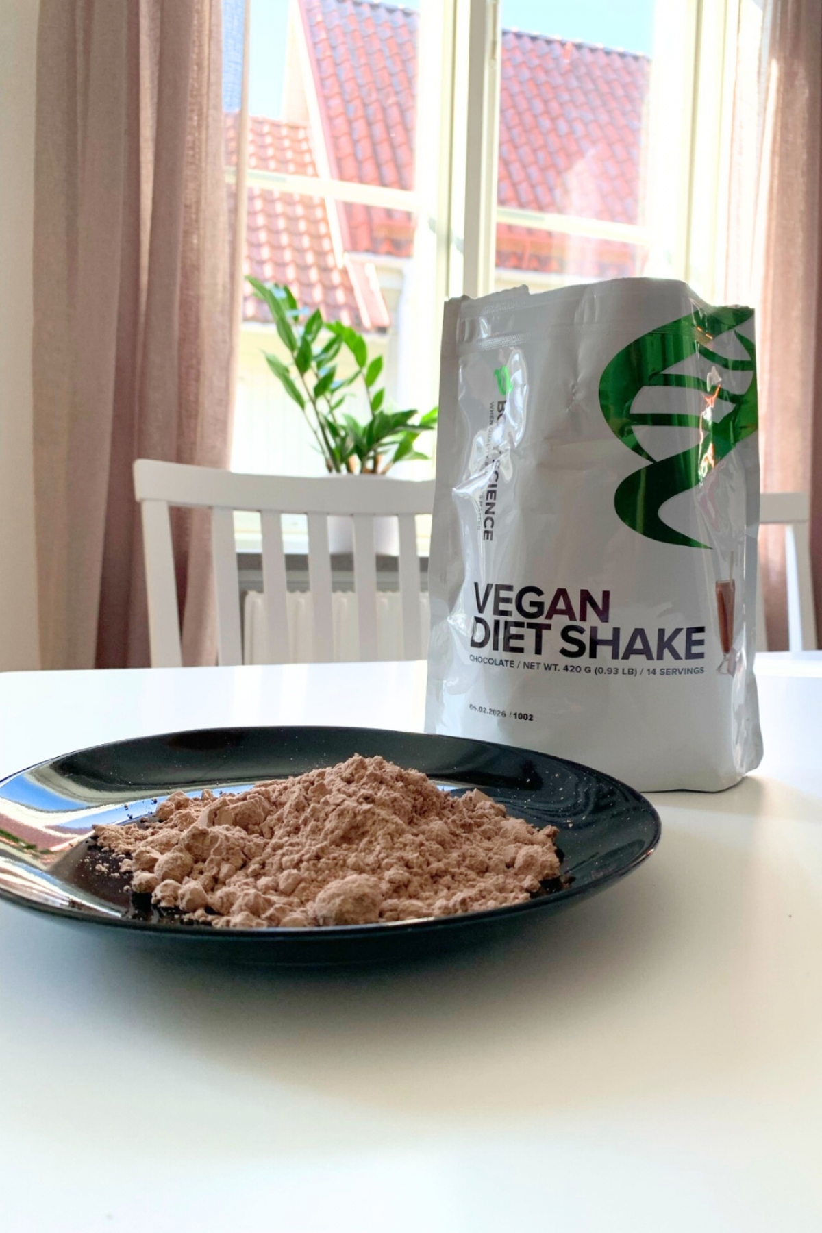 Portion av pulver på tallrik med påsen bakom, Body Science Vegan Diet Shake