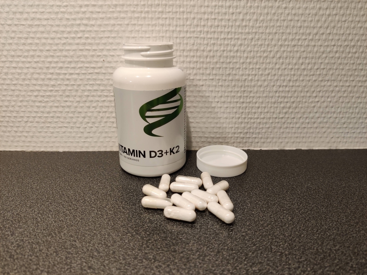 Body Science Vitamin D3+K2 med utspridda kapslar på bänkskiva, foto taget av oss under testet