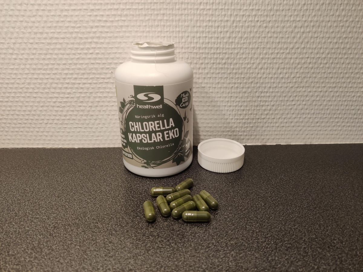 Healthwell Chlorella Kapslar EKO med kapslar på bänkskiva, taget av oss under testet