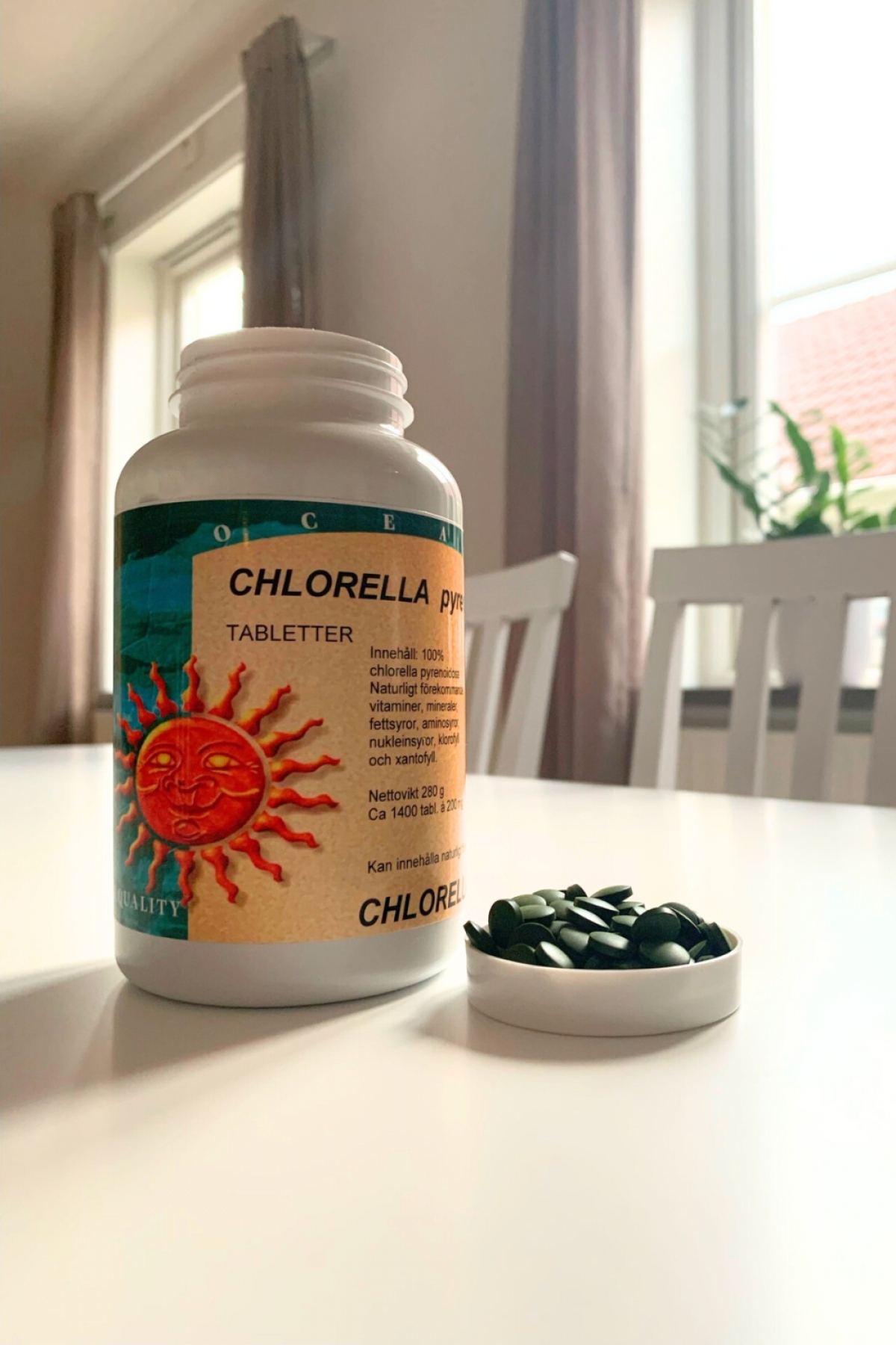 Öppnad Colomaris-burk med chlorella-tabletter framme på bordet