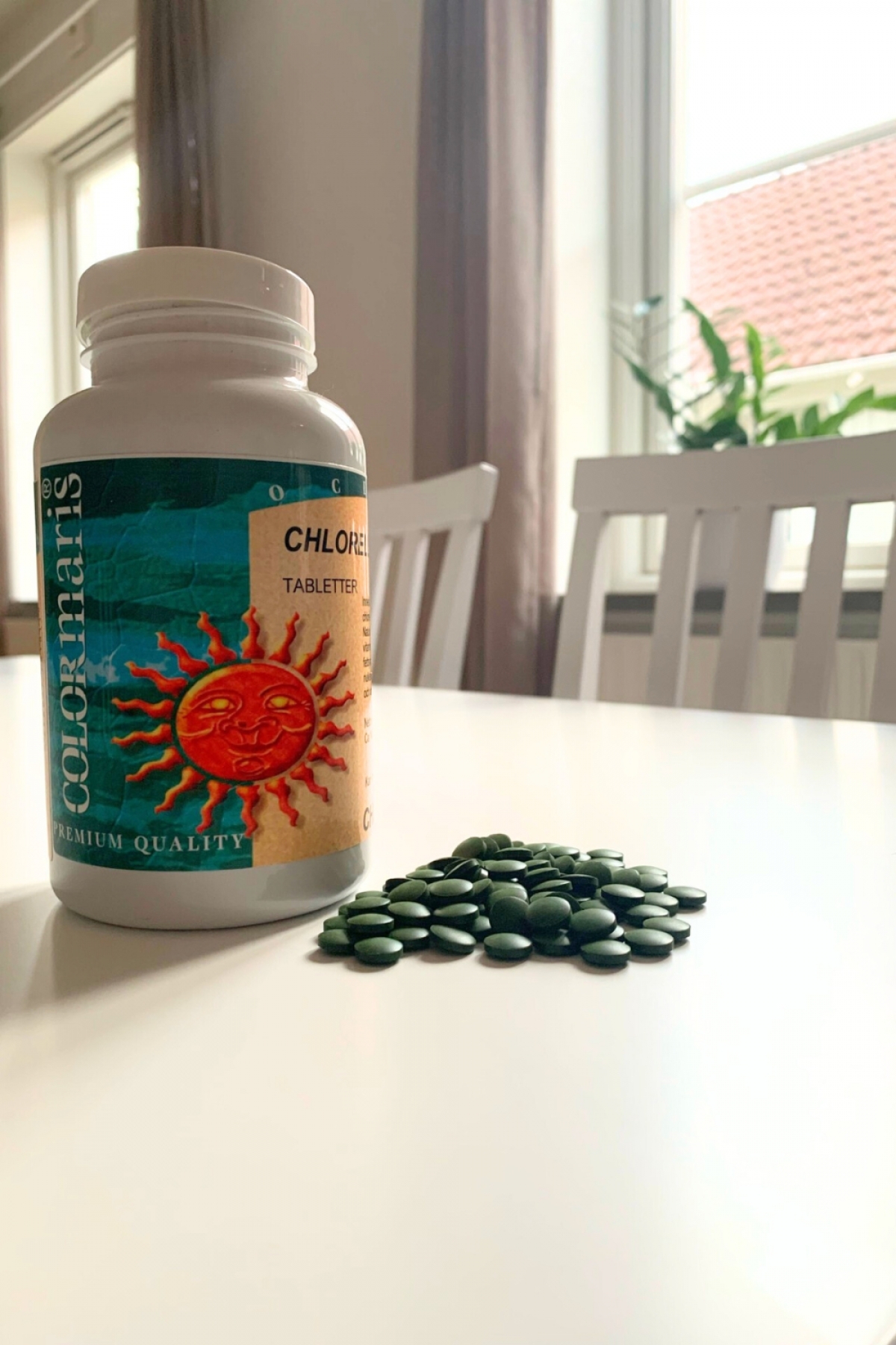 Colomaris Chlorella och en hög tabletter på vitt bord, foto från vårt test