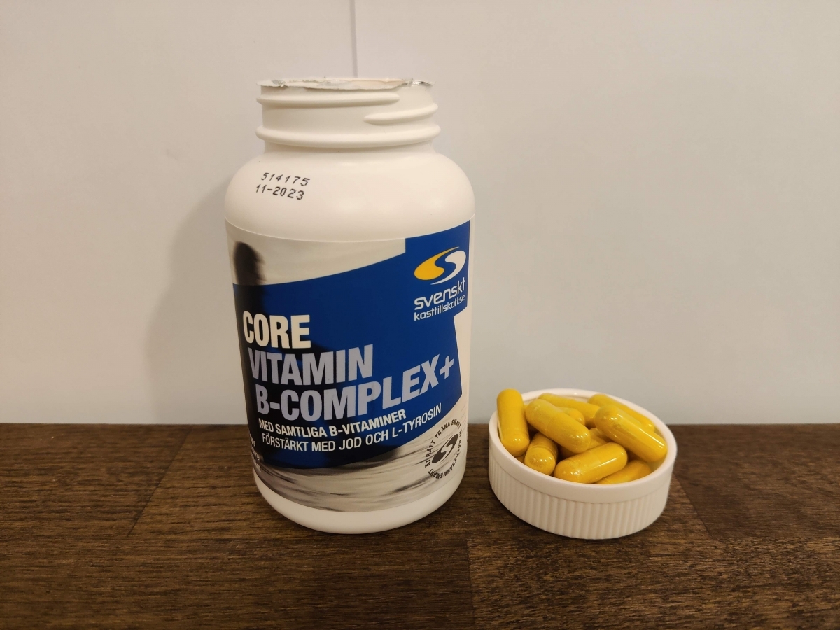 Närbild på Core B-Complex och kapslar i locket på träbord, taget av oss
