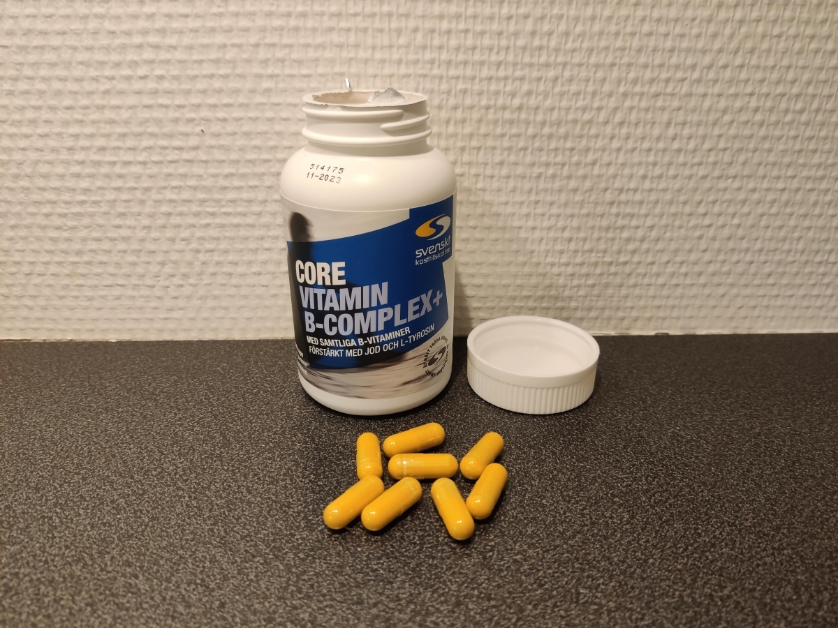Öppen burk Core Vitamin B-Complex+ med gula kapslar på bänken, foto taget av oss under testet