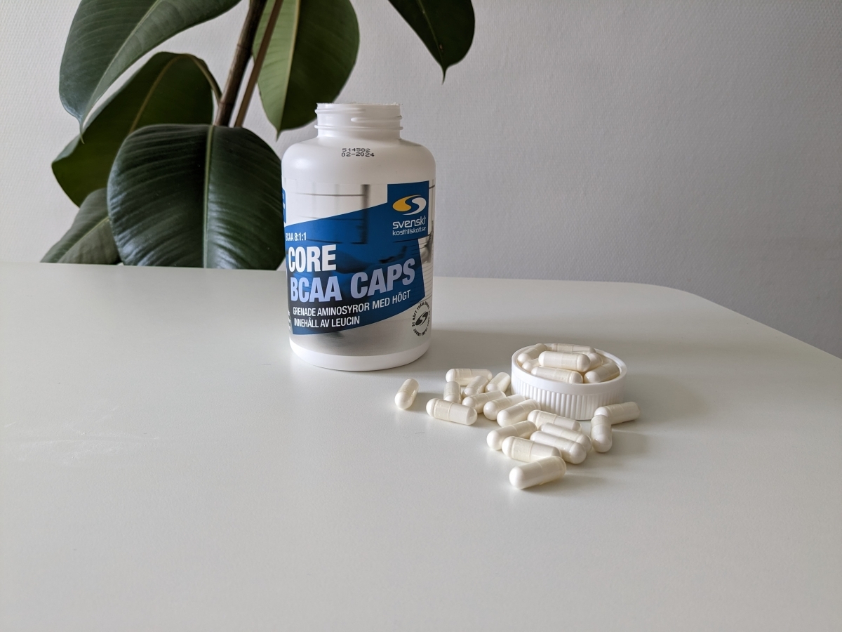 Core BCAA Caps burk och kapslar på vitt bord i dagsljus foto av oss under testet