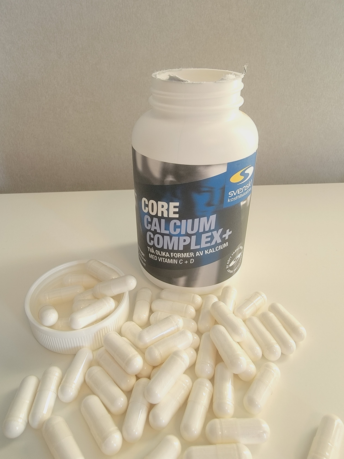 Core Calcium Complex+ öppnad burk med kapslar utspridda på bordet, foto taget av oss under testet