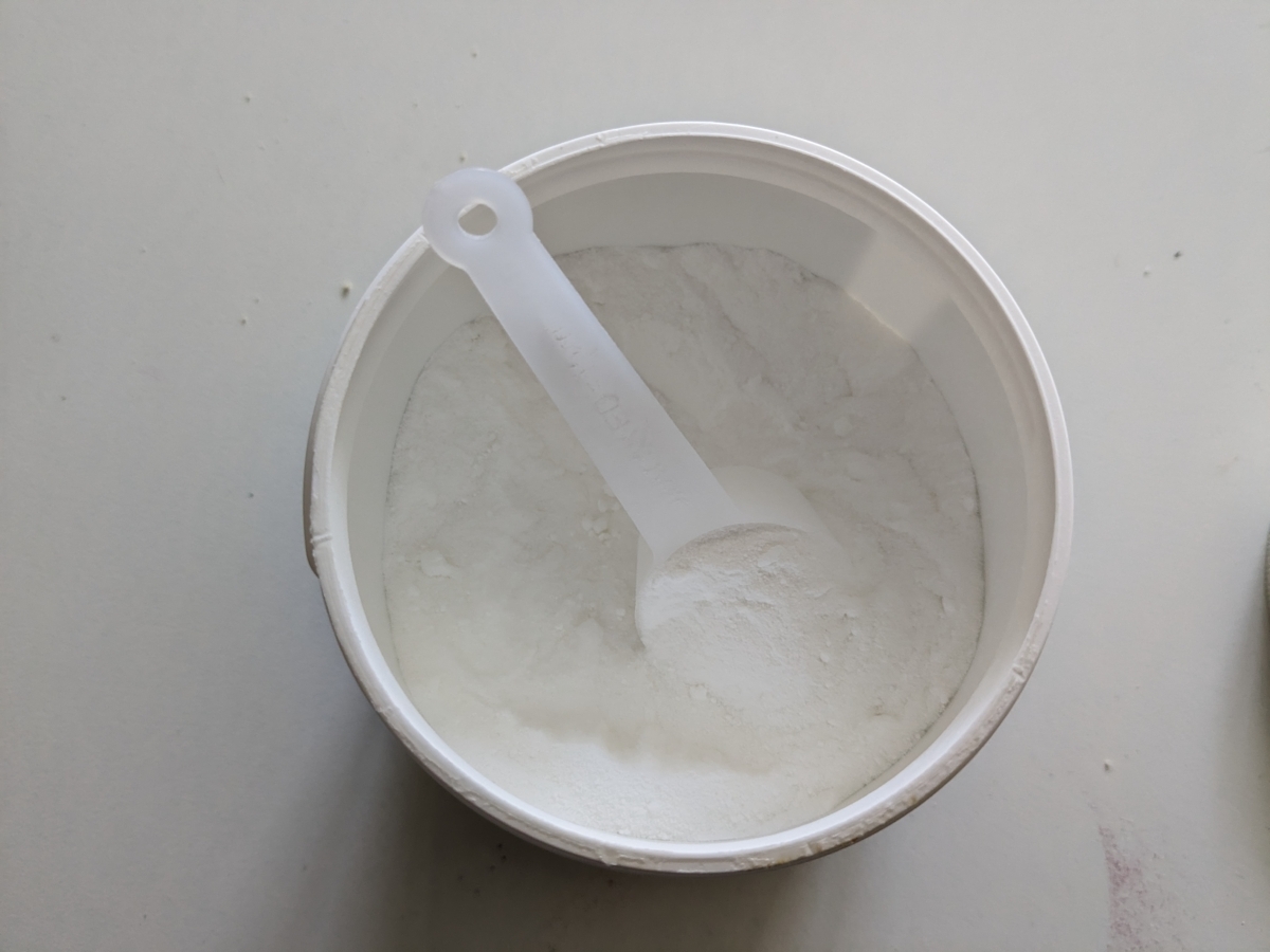 Öppnad burk Core Creatine Pro med skopa i mjölfint pulver fotad i vårt test