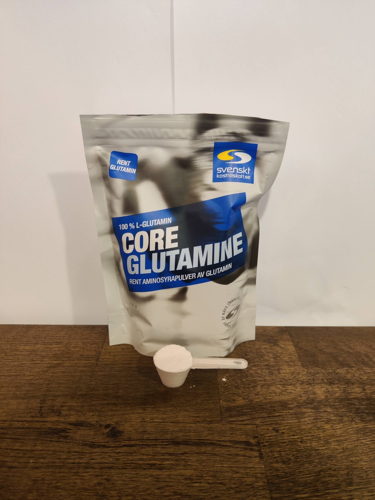 Core Glutamine och skopa på träbord i varmt kvällsljus, vår egen bild
