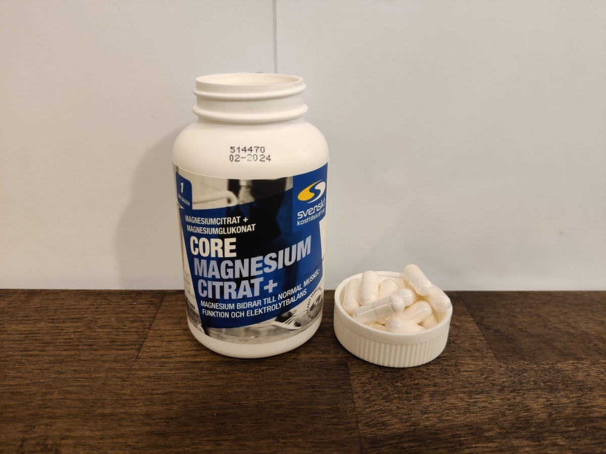 Core Magnesium Citrat på träbord med kapslar i locket, fotograferat av oss