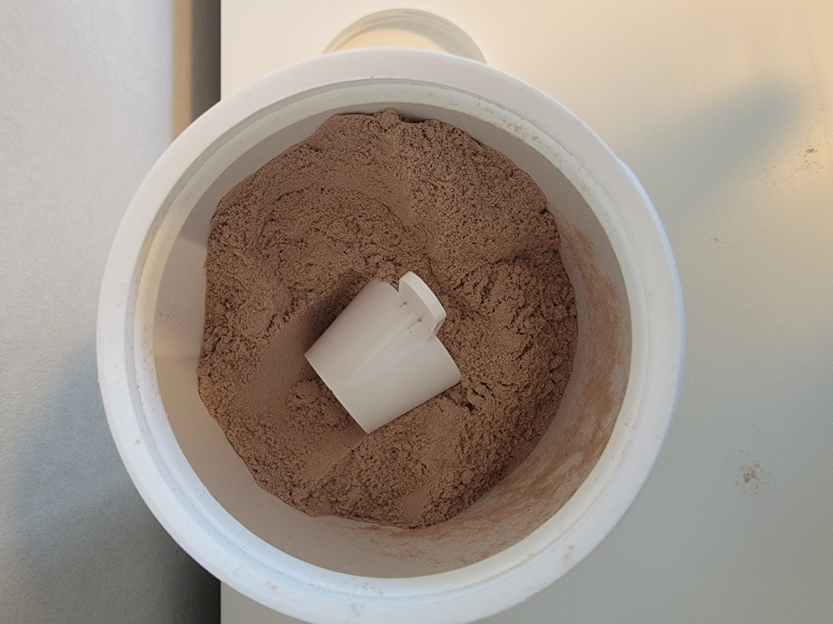 Insidan av burken med chokladpulver och skopa, tagen av oss under användning
