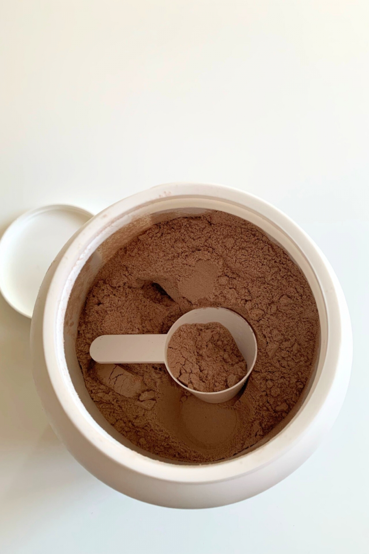 Öppen burk med finmalt chokladpulver och skopa i Core Protein Pro