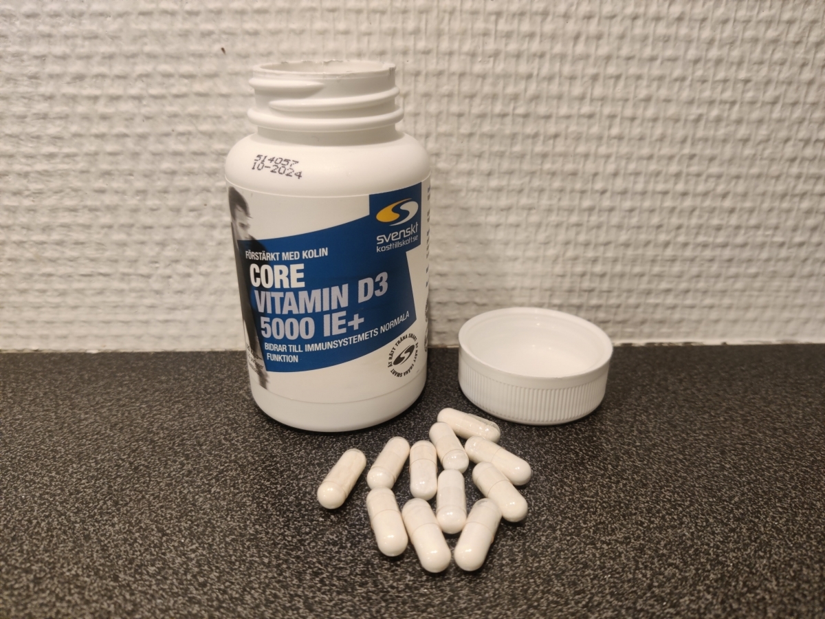 Core Vitamin D3 5000 IE+ öppnad burk med vita kapslar på bänkskiva, fotograferad av oss under testet