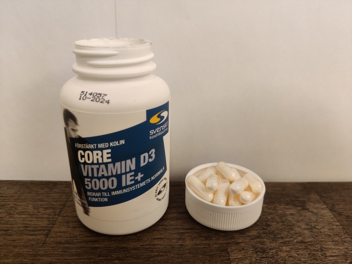 Core Vitamin D3 5000 IE+ på träbord med kapslar intill, foto från vår recension
