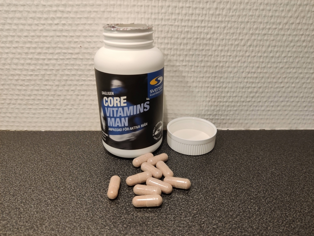 Core Vitamins Man med öppnad burk och kapslar på bänken, foto taget av oss