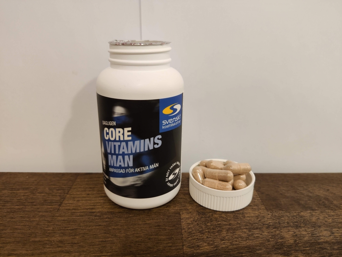 Core Vitamins Man på träskiva med några kapslar i locket, vårt foto