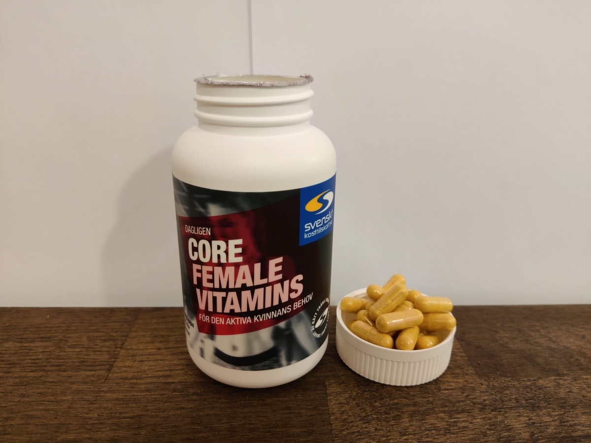 Core Vitamins Woman på träbord med dagens kapslar bredvid