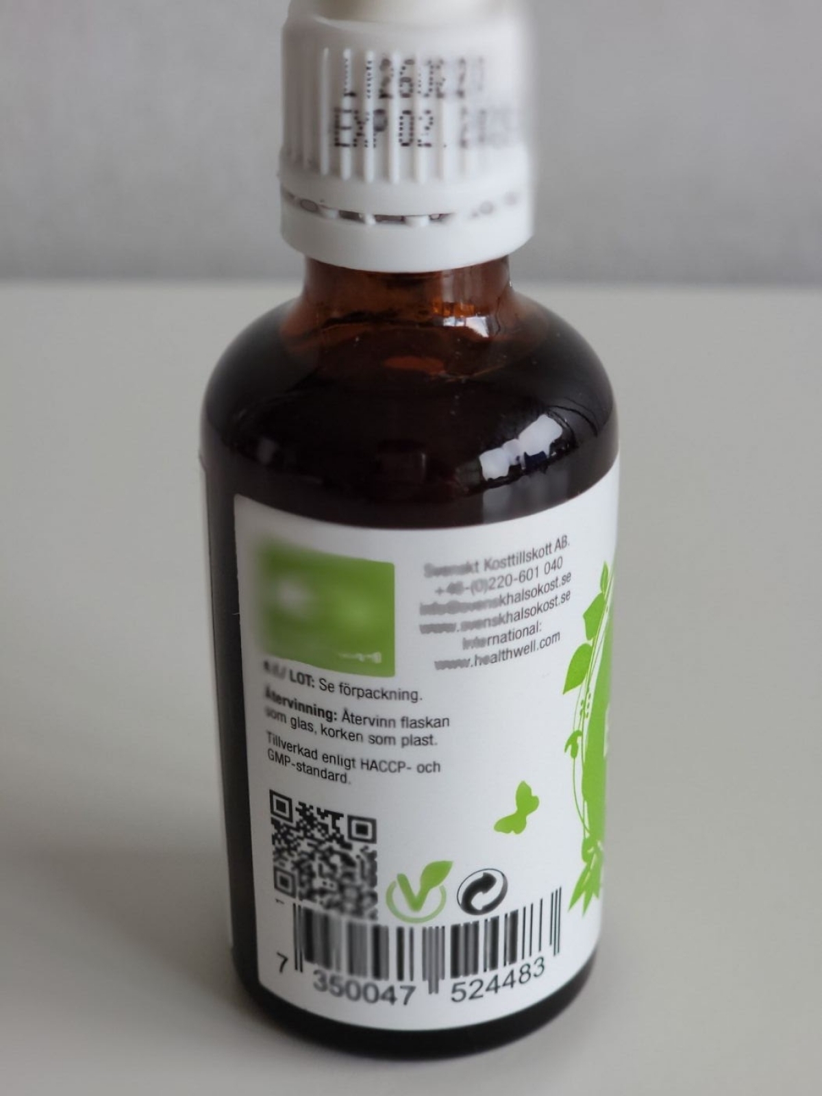 Detalj på batchnummer och hållbarhet på Healthwell-flaskans baksida