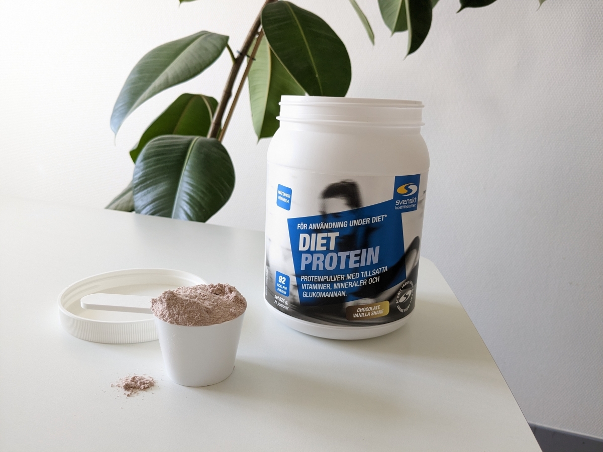 Diet Protein burk och uppmätt skopa på bord i dagsljus, tagen av oss