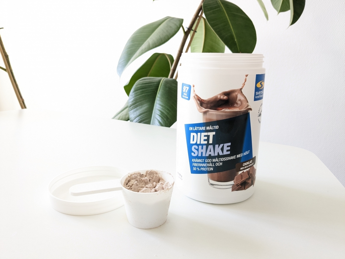 Diet Shake choklad med skopa på bord i dagsljus, fotad av oss under testet