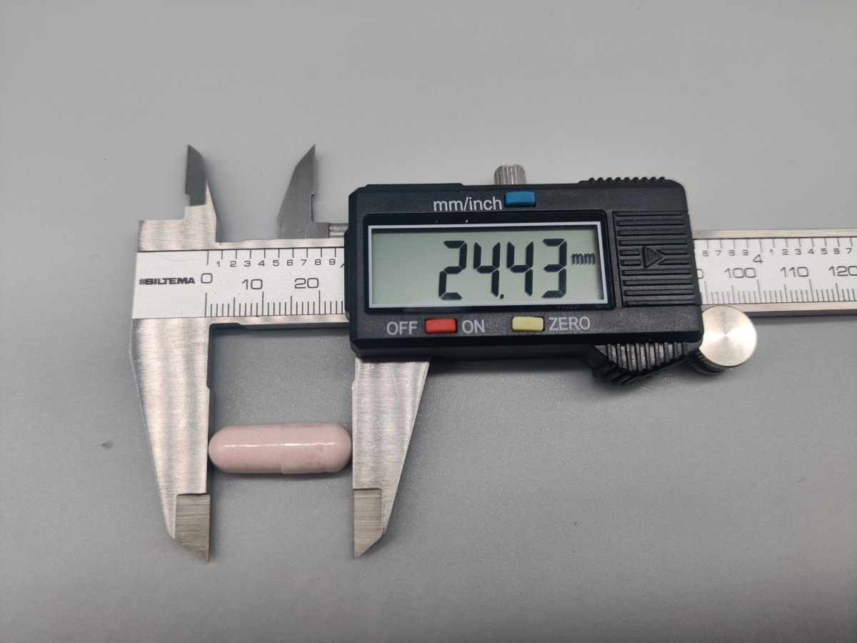 Skjutmått som mäter kapselns längd till cirka 24,4 mm