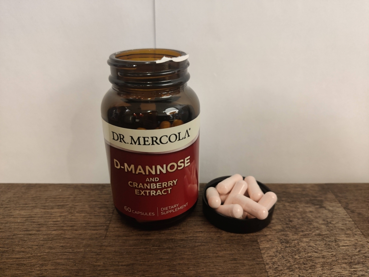 Dr Mercola D‑Mannose kapslar bredvid burken på träbord i mjukt dagsljus