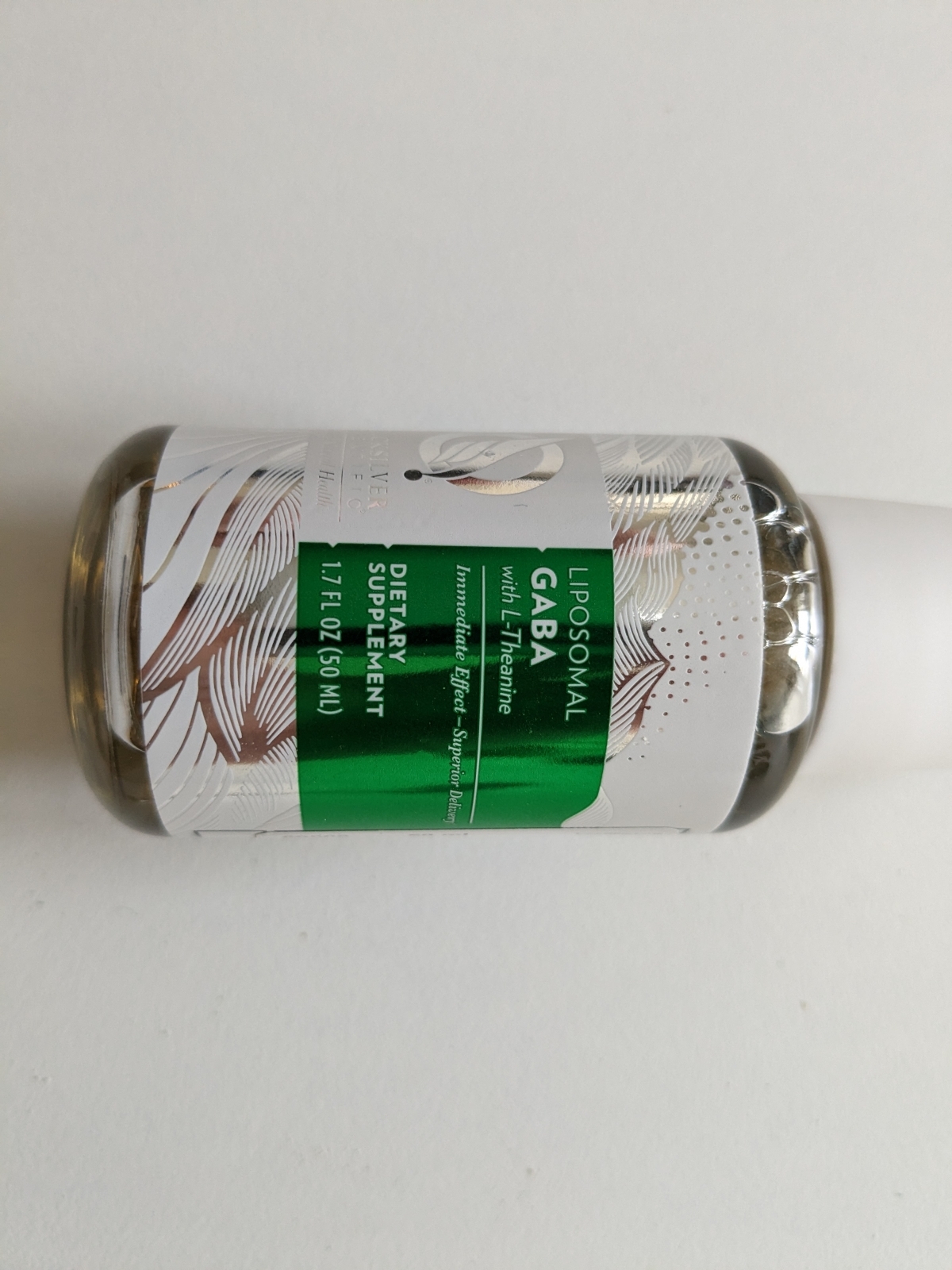 Flaskan liggande mot vit bakgrund, Liposomal GABA + <a href='https://www.kostnord.se/kosttillskott/teanin'>L-teanin</a>, eget foto