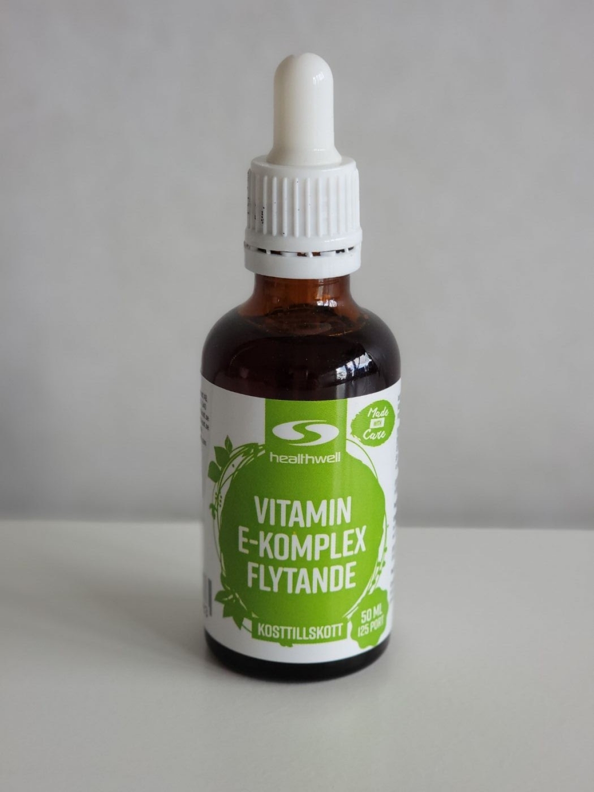 Framsida på Healthwell Vitamin E Komplex Flytande med dospipett fotograferad efter flera veckors användning