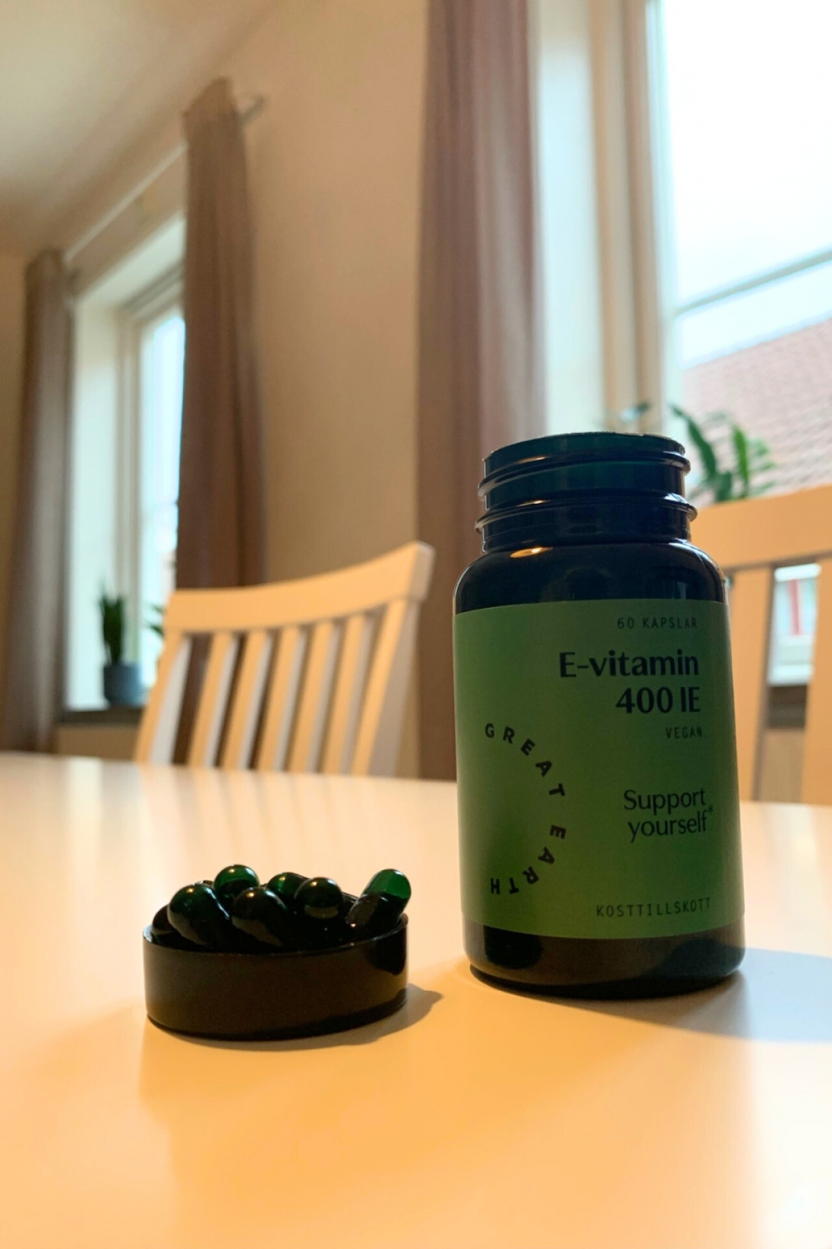 Öppen burk med mörkgröna kapslar Great Earth E‑vitamin, tagen av oss