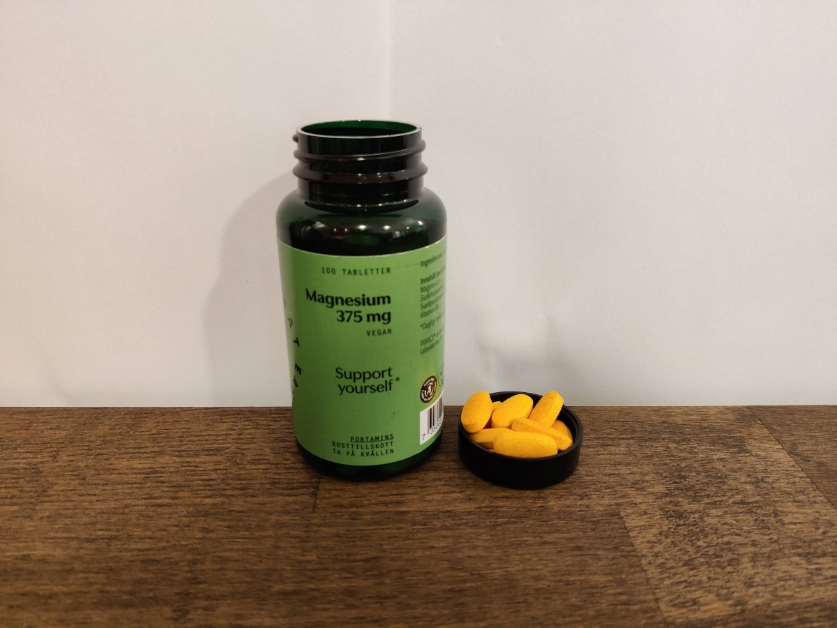 Burk med Great Earth Magnesium 375 mg och några tabletter bredvid, foto av oss