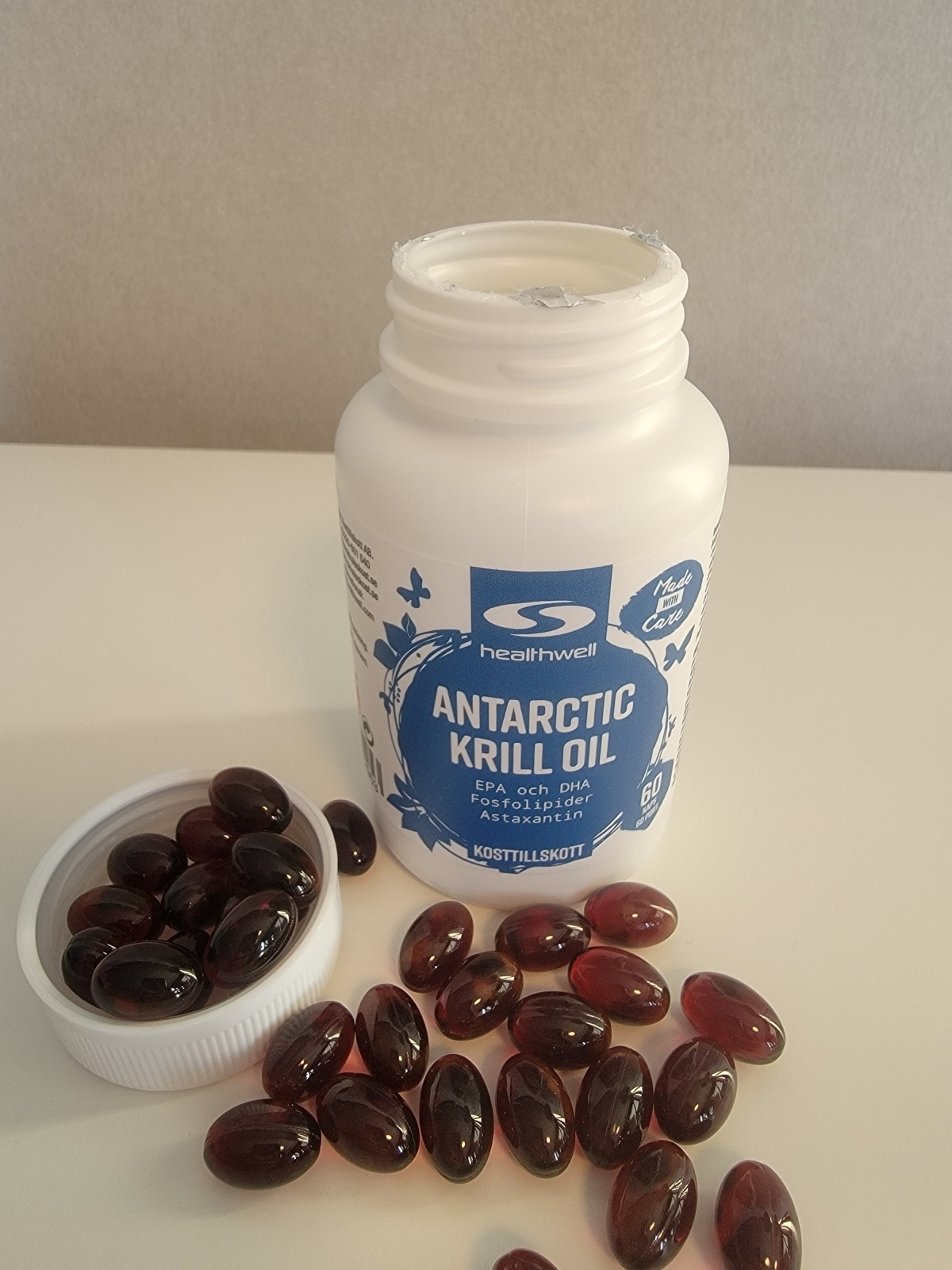 Vår egen bild av Healthwell Antarctic Krill Oil – öppnad burk med djupröda, små kapslar intill