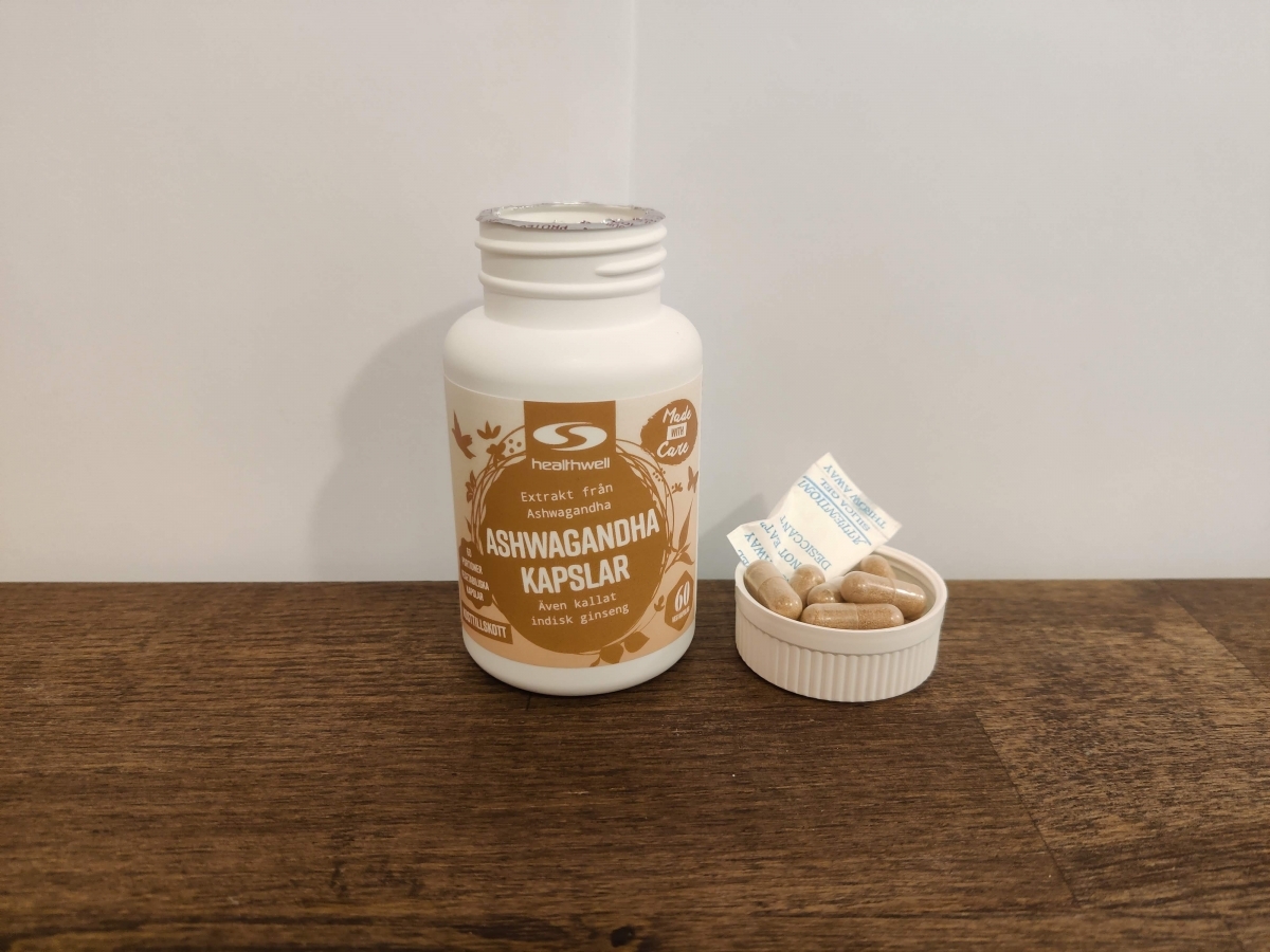 Healthwell Ashwagandha Extrakt öppnad burk med kapslar på träbord, foto taget av oss under testet