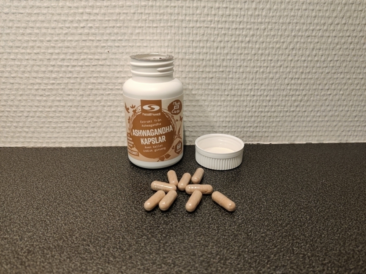 Healthwell Ashwagandha Extrakt och ljusbruna kapslar på bänkskiva, taget av oss under testet
