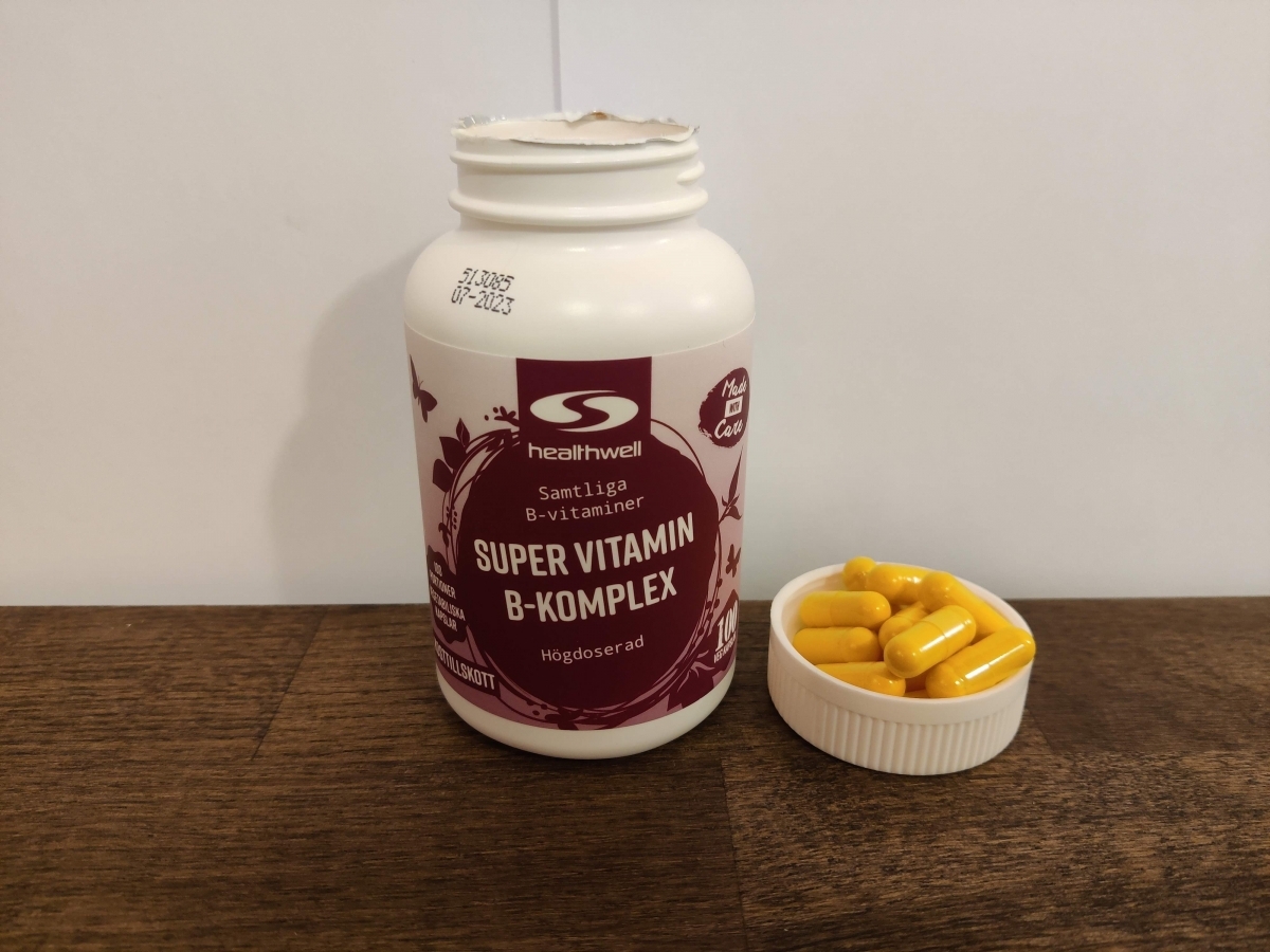 Healthwell Super Vitamin B-komplex på träbord med kapslar bredvid burken, från vårt eget test
