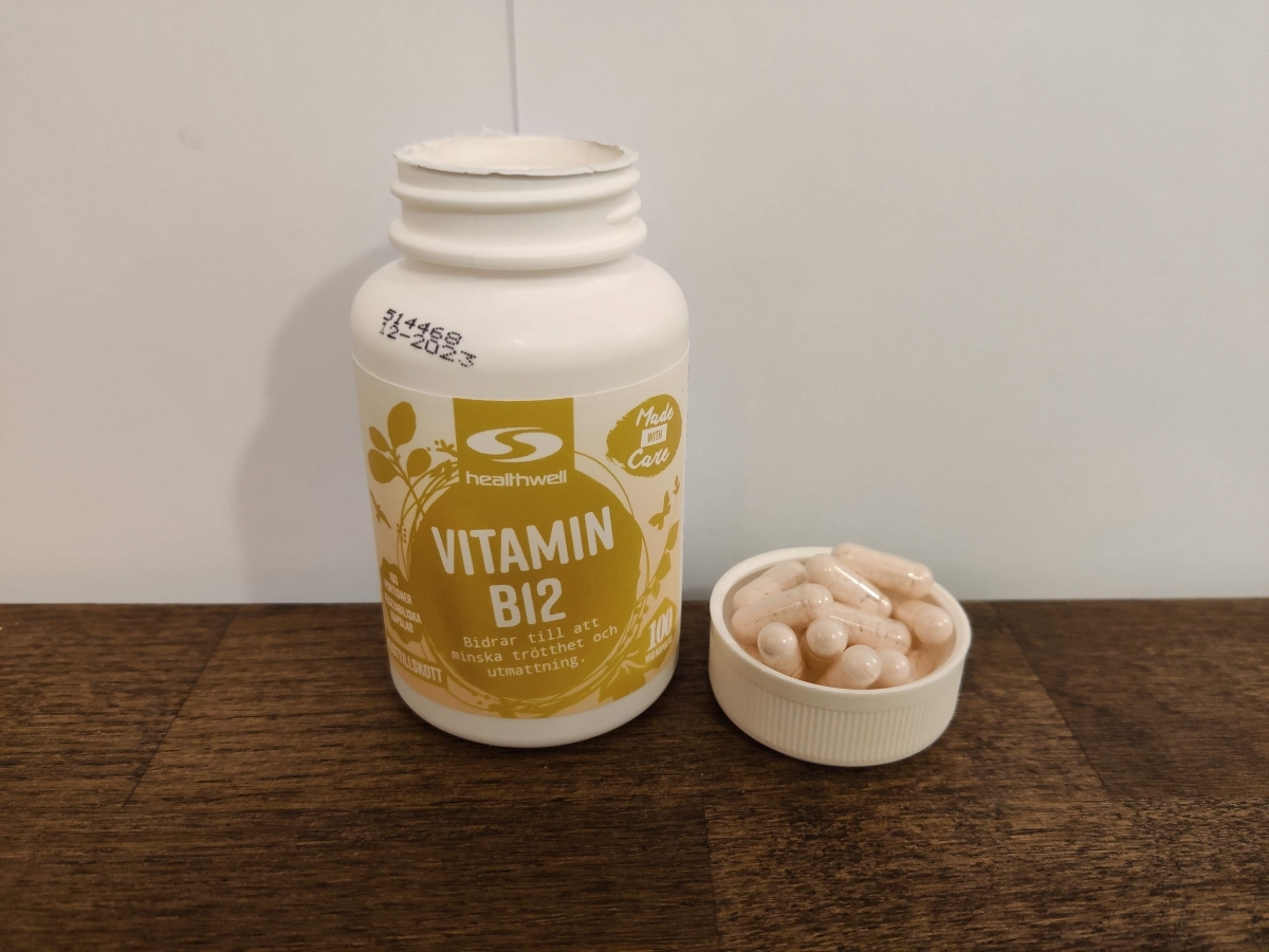 Healthwell B12 med kapslar intill locket på köksbord, egen bild