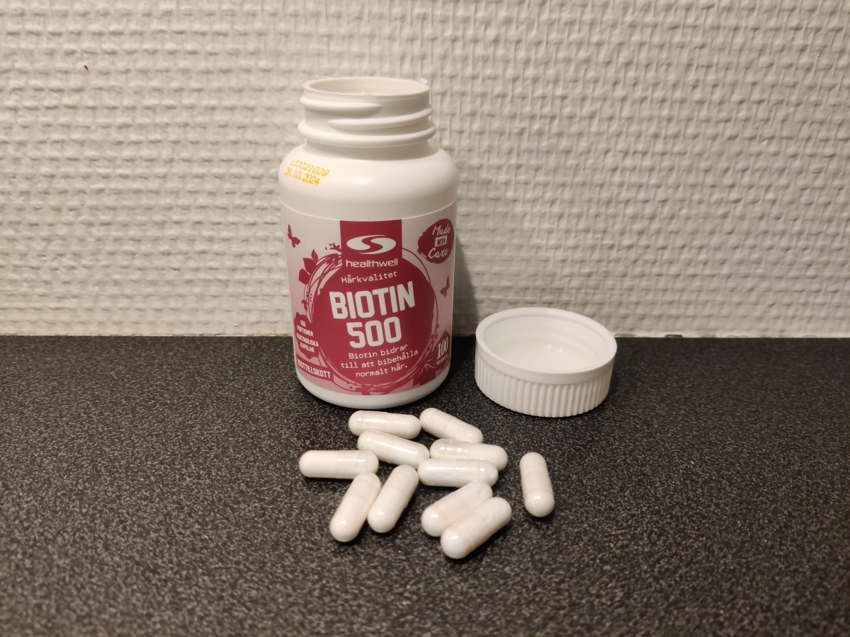 Healthwell Biotin 500 öppnad burk med kapslar på mörk bänk, foto taget av oss under testet