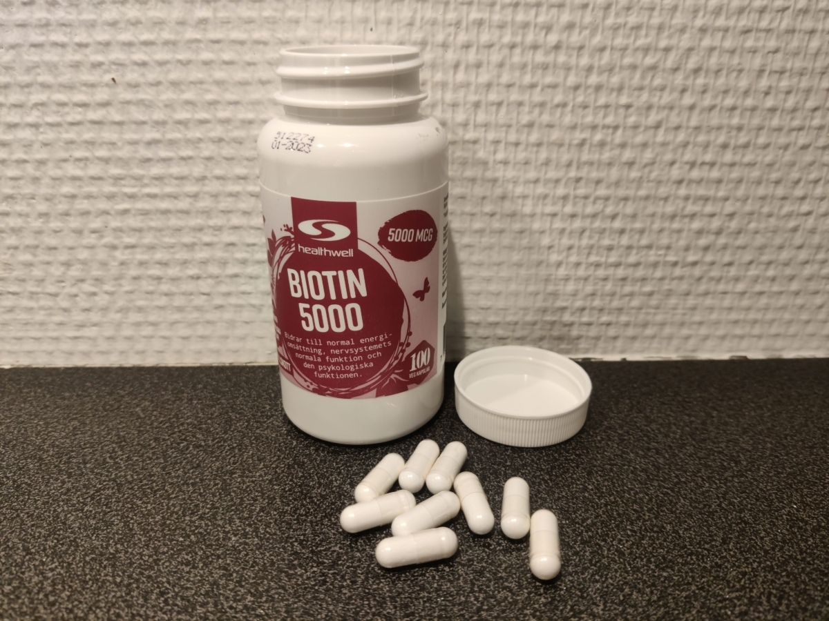 Healthwell Biotin 5000 med öppet lock och kapslar på bänkskiva foto av oss