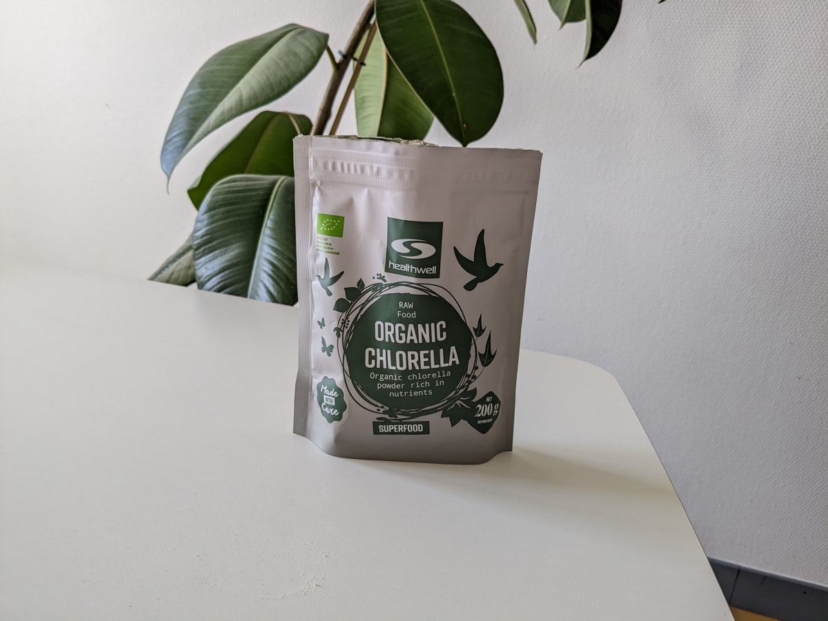 Healthwell Organic Chlorella 200 g på vårt bord under testet med växt i bakgrunden