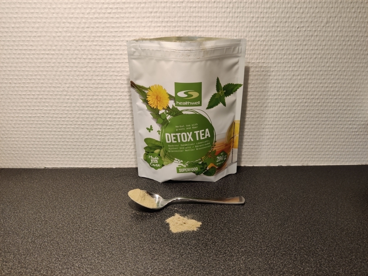 Healthwell Detox Tea med tesked pulver framför påsen, foto taget av oss