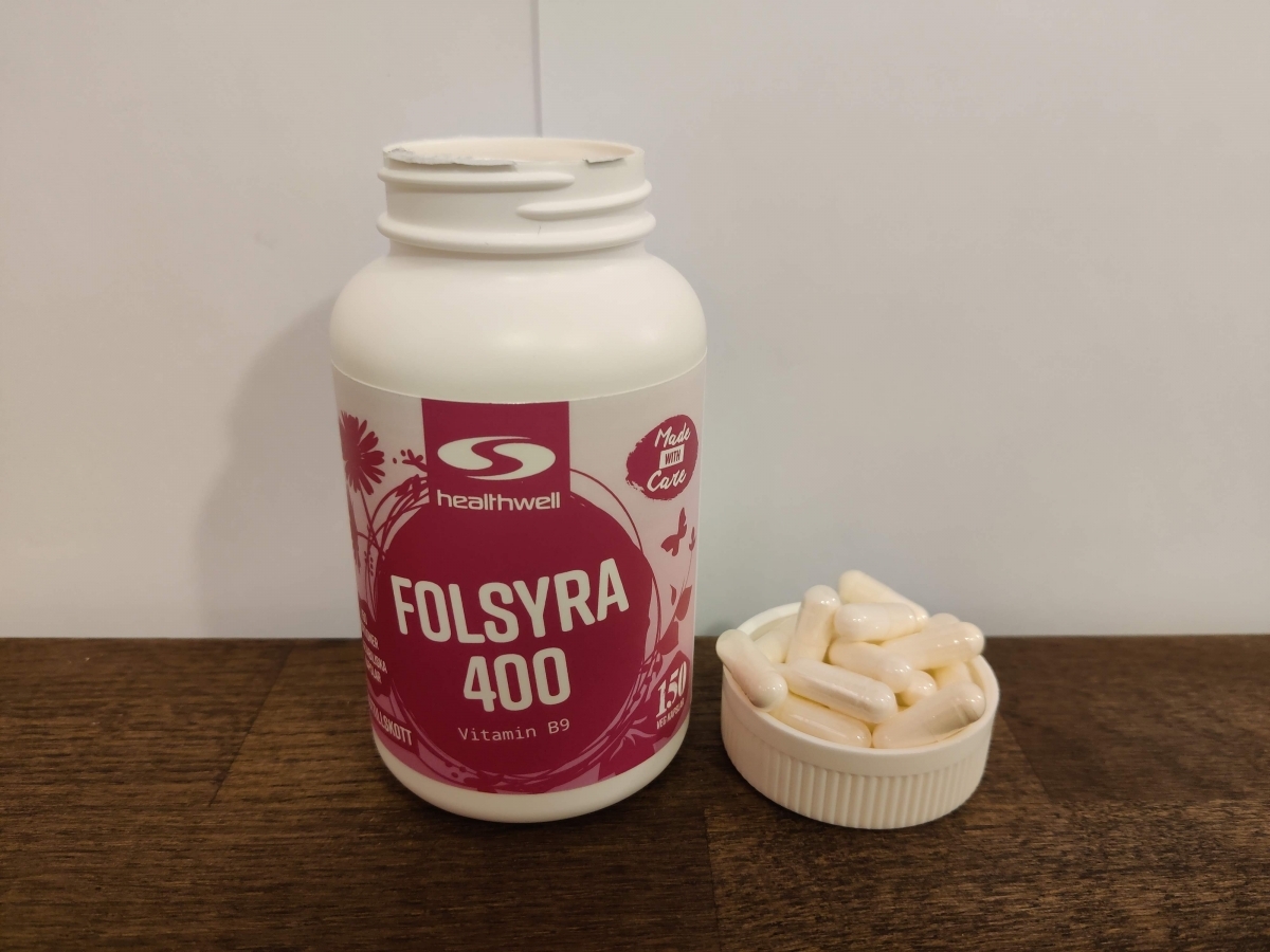 Healthwell Folsyra 400 med några kapslar placerade bredvid burken, fotograferad av oss