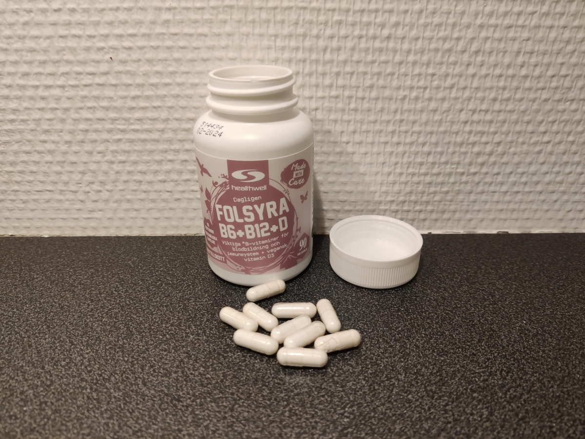 Healthwell Folsyra B6 B12 D med öppet lock och kapslar på bänkskiva, foto taget av oss under testet