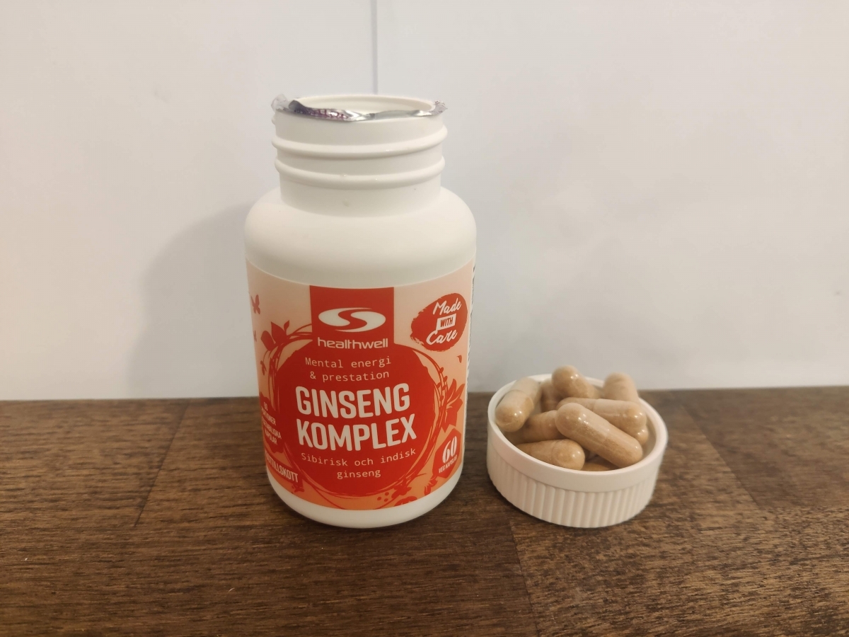 Healthwell Ginseng Komplex på träbord med kapslar bredvid egen testbild