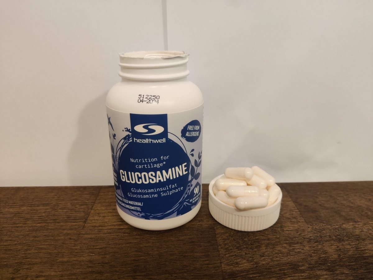 Healthwell Glukosamine med några kapslar bredvid burken fotograferad av oss