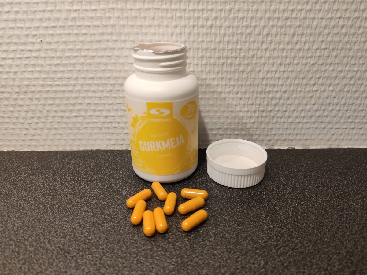 Öppnad burk med gulorange kapslar av Healthwell Gurkmeja Extrakt, foto av oss