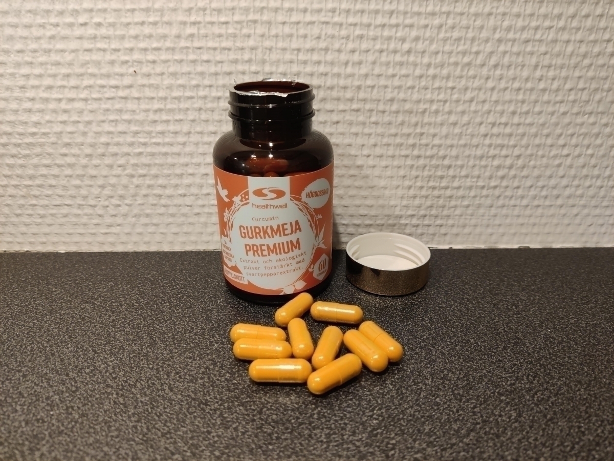 Öppen burk och utspridda kapslar av Healthwell Gurkmeja Premium på köksbänken